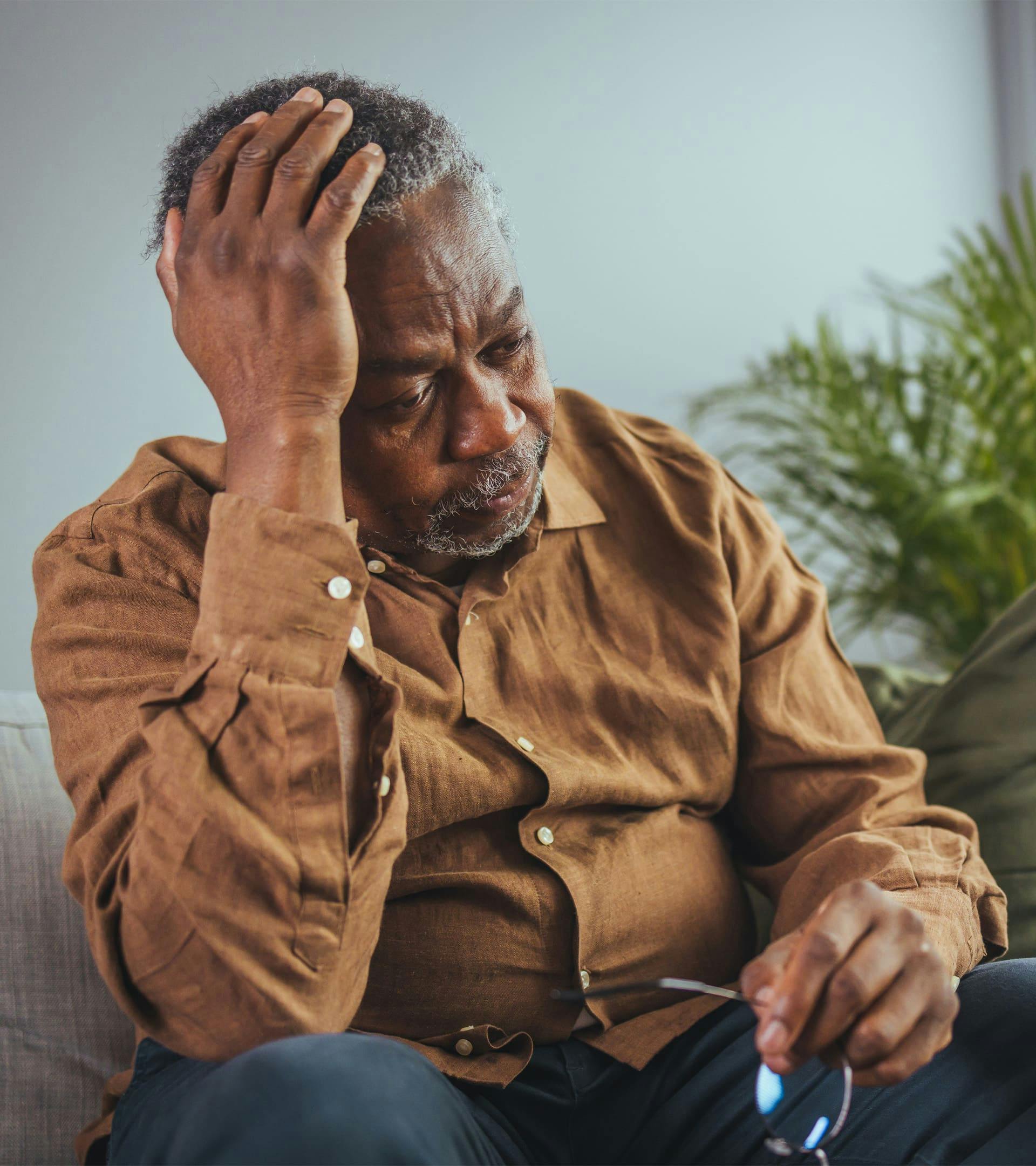 Man sitting down with hand on head