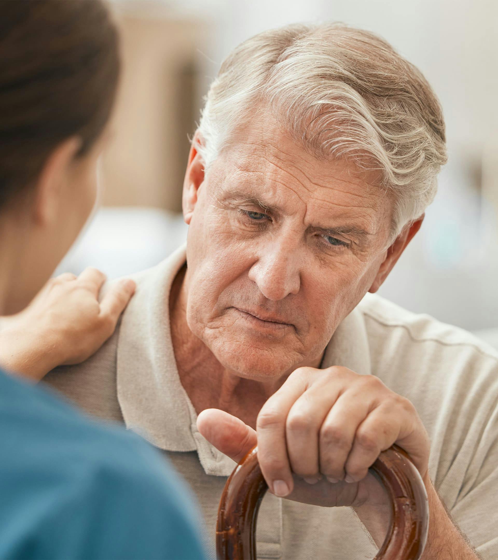 Older man with cane looking in pain