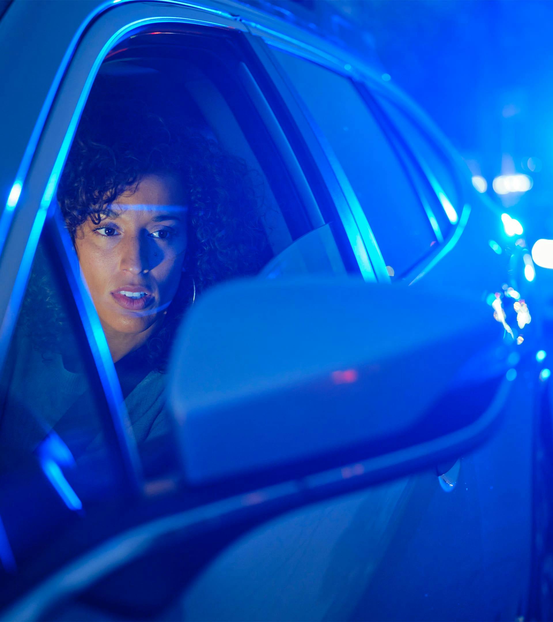 Woman looking at side mirror back at police after being pulled over