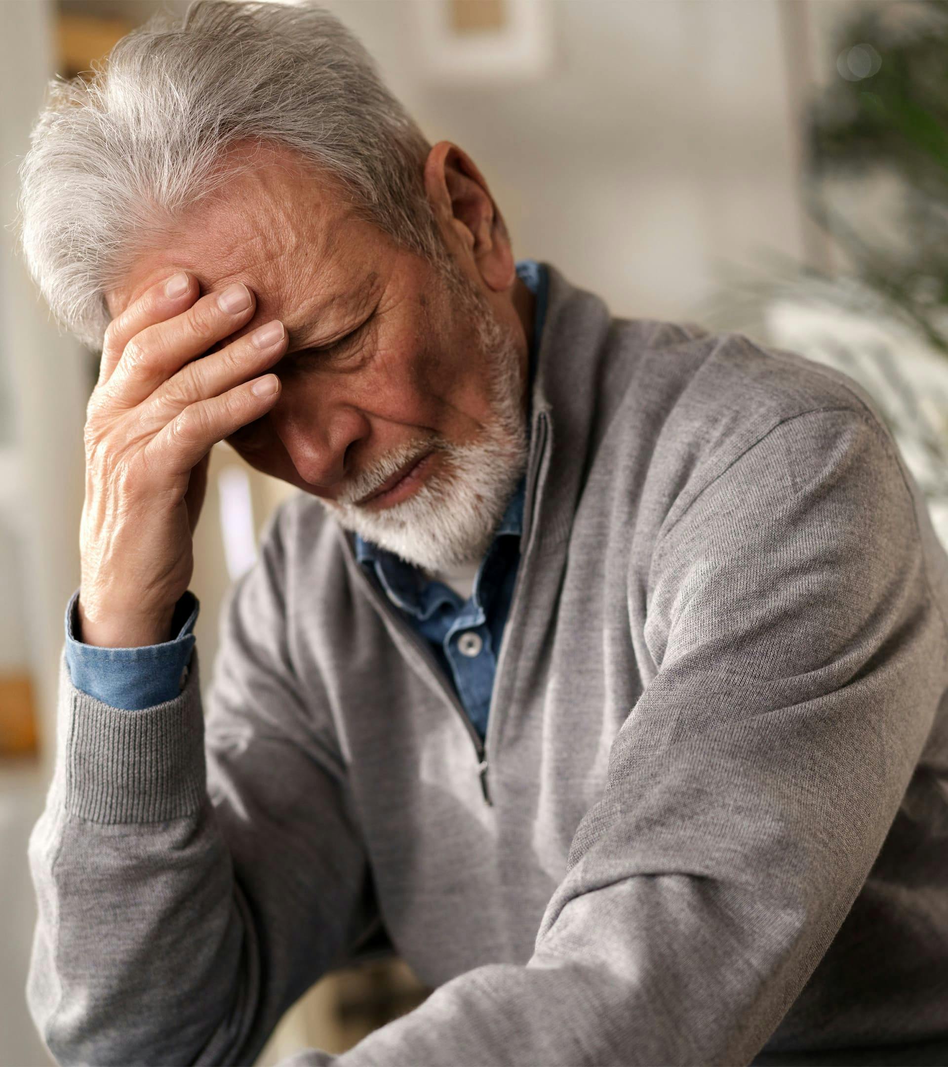 Man with head down and hand on forehead