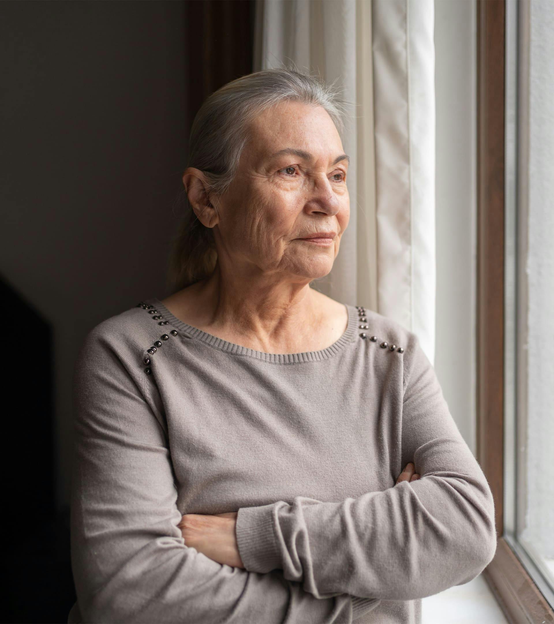 Woman with arms crossed looking out the window