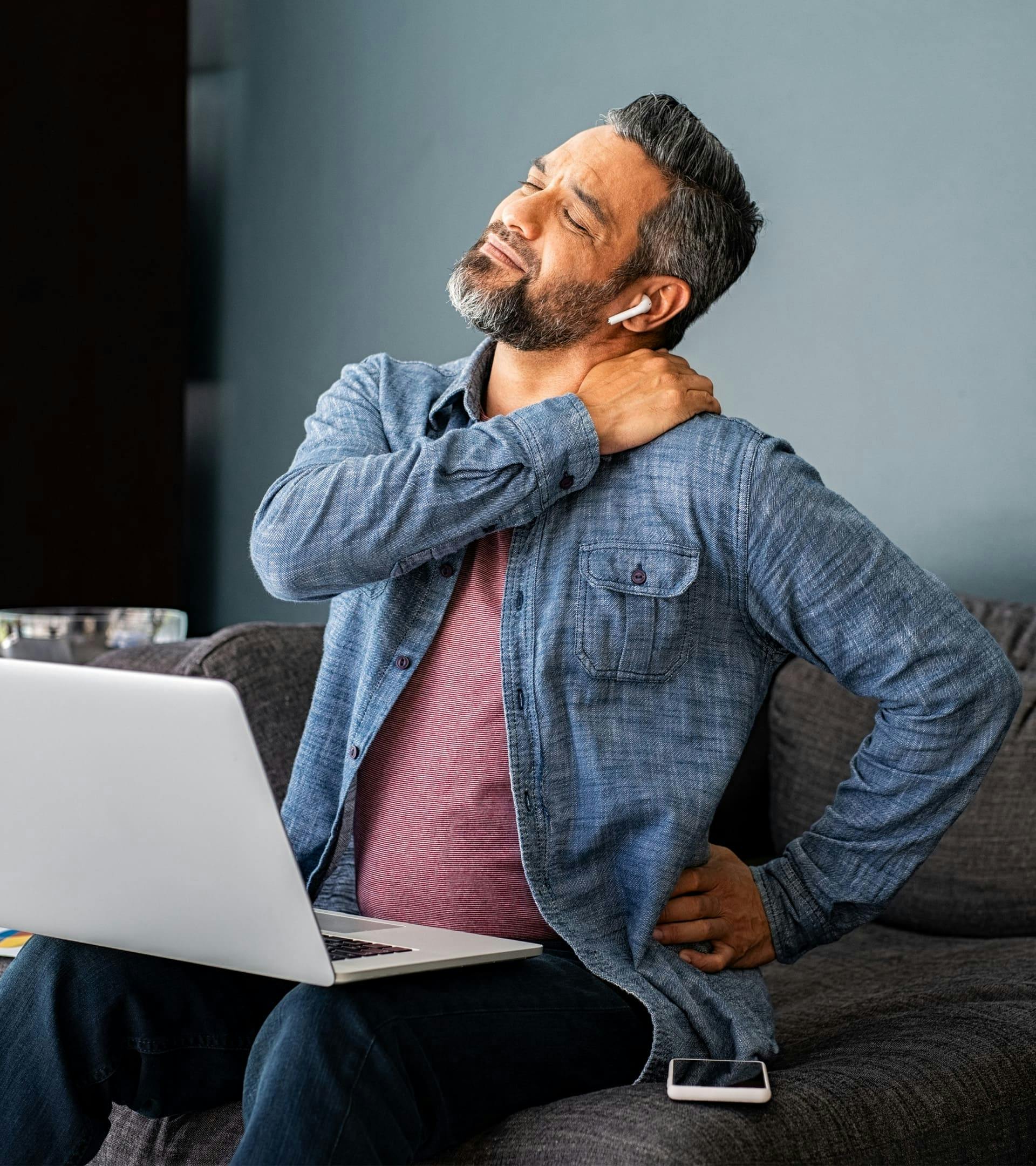 Man sitting with laptop holding neck in pain