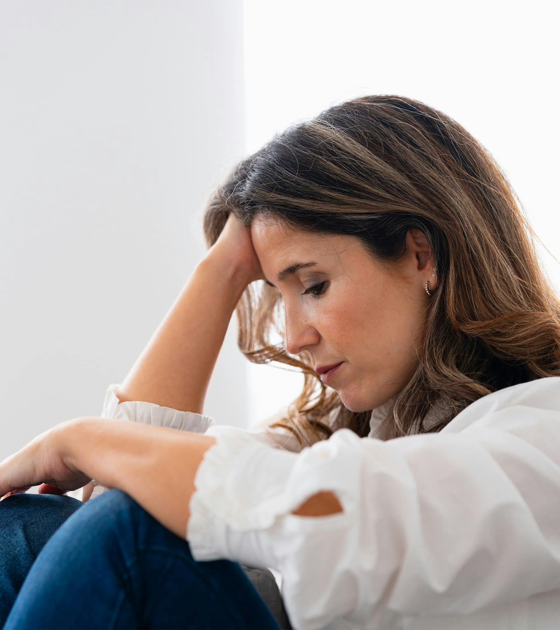 Woman looking down with hand running through hair