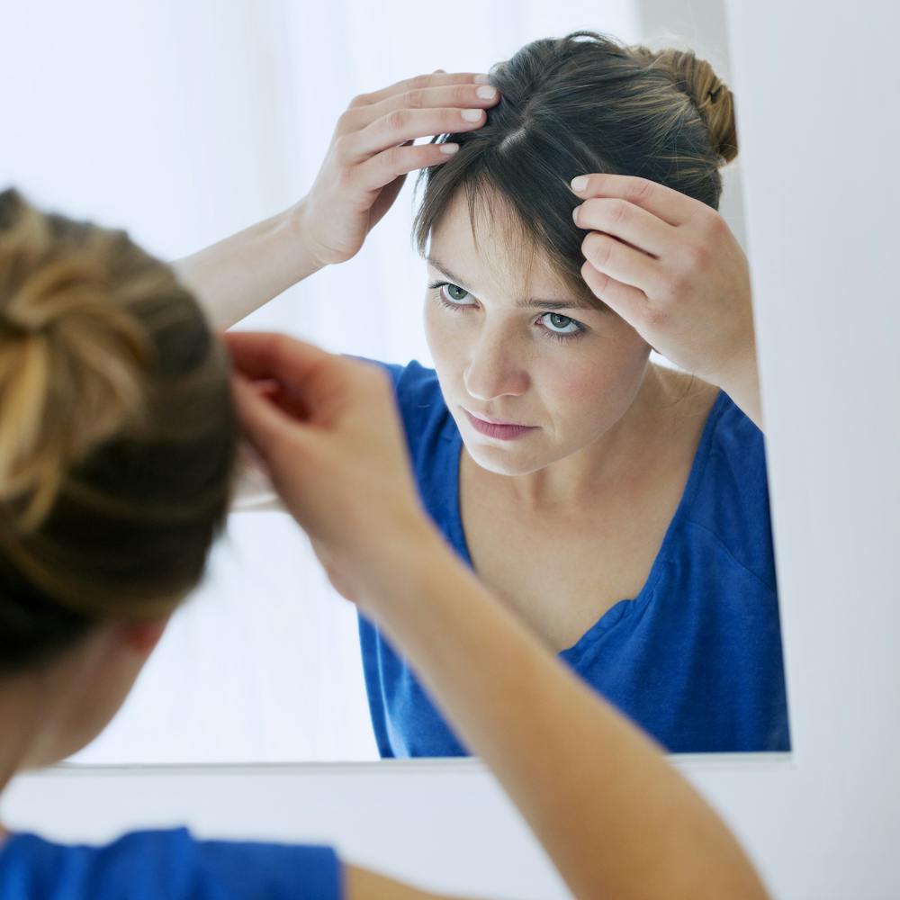 woman looking at her hair in the mirror