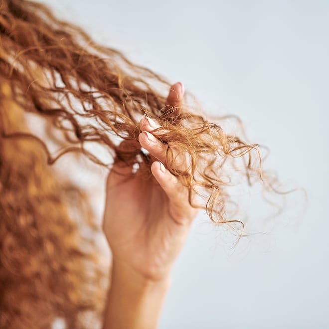 woman's curly hair as she combing her fingers through it