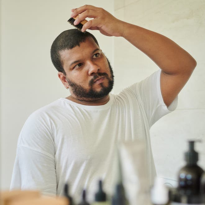 man looking in mirror and brushing his hair