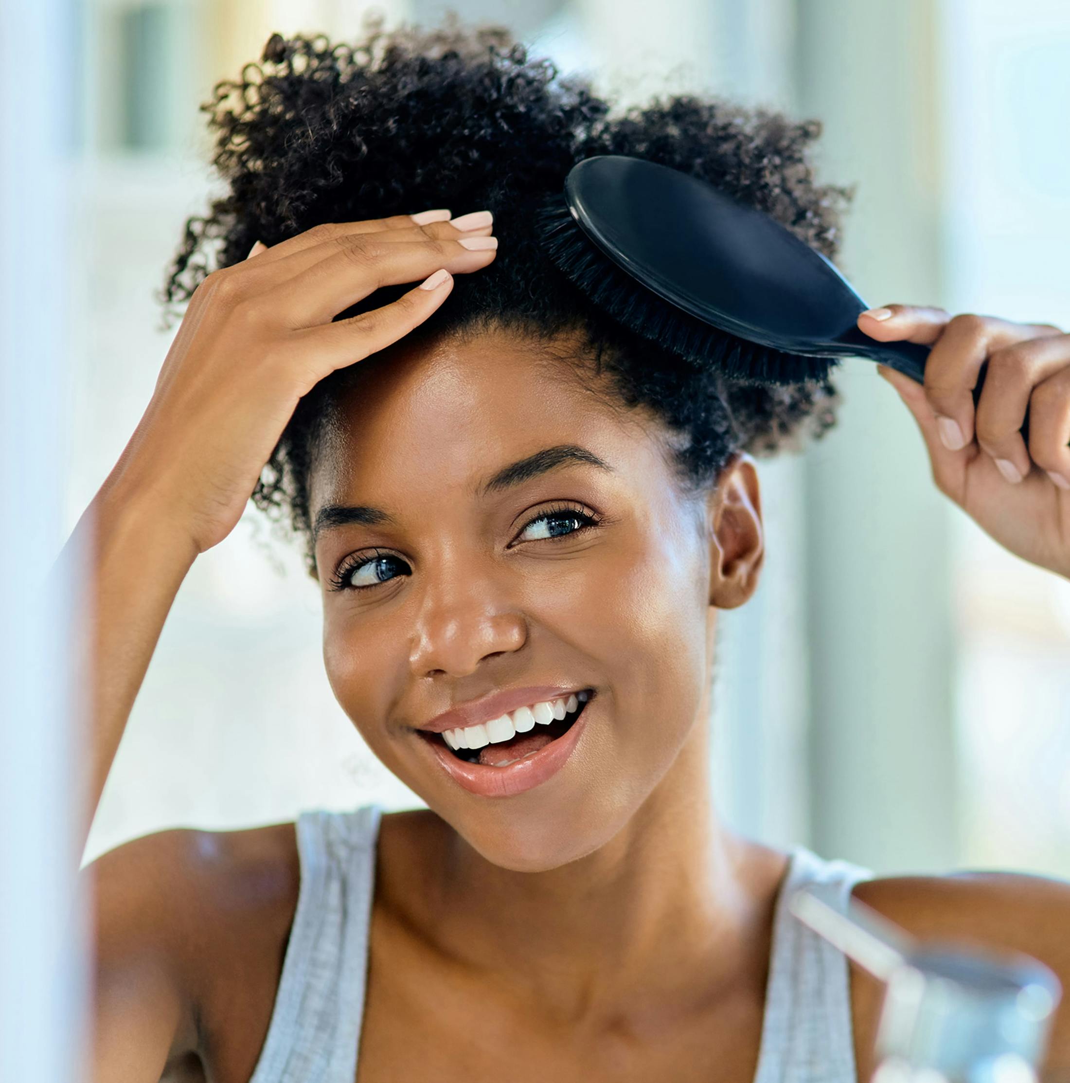 woman with curly hair brushing her hair in mirror