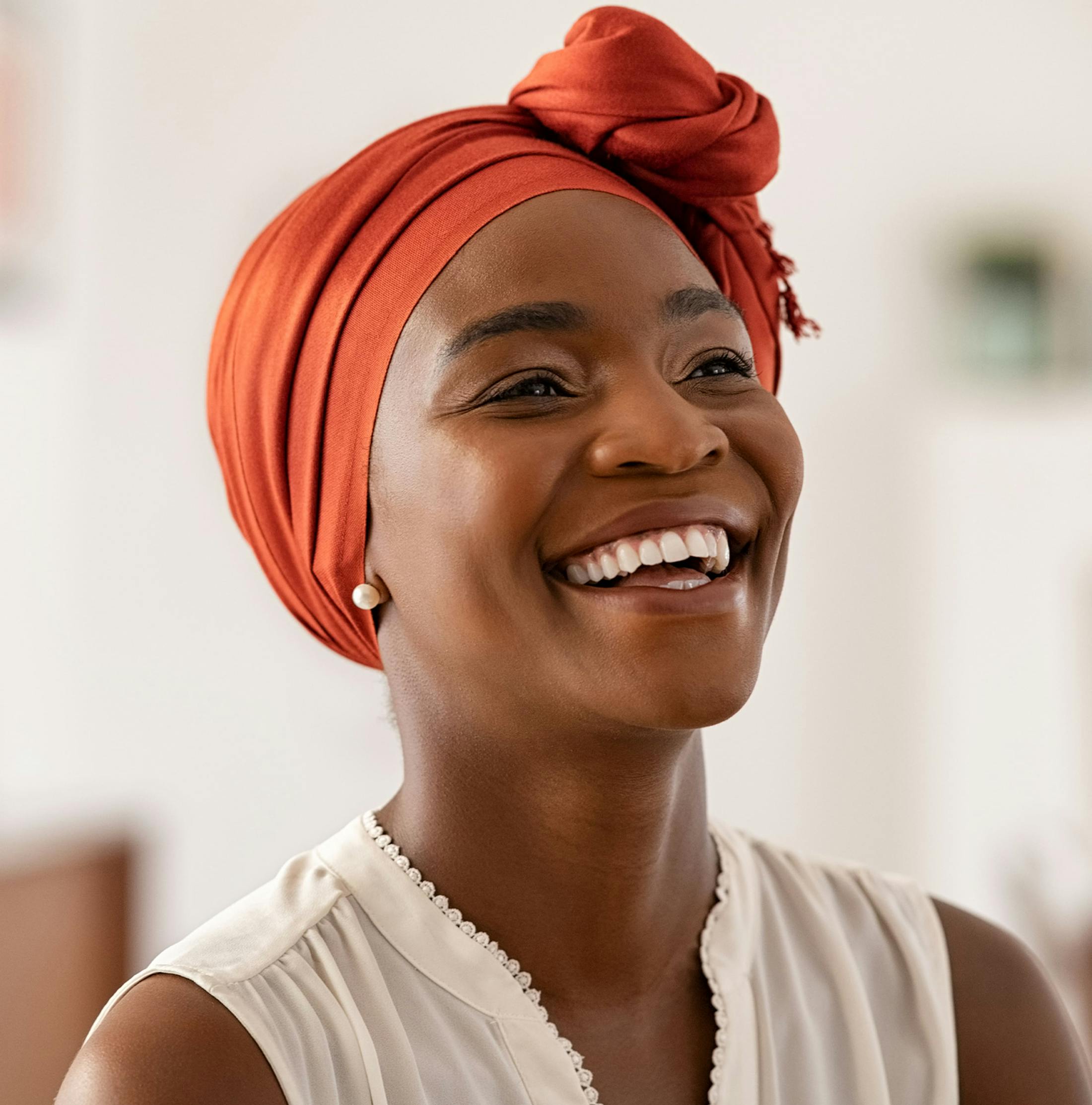 woman smiling with her head wrapped in a head scarf