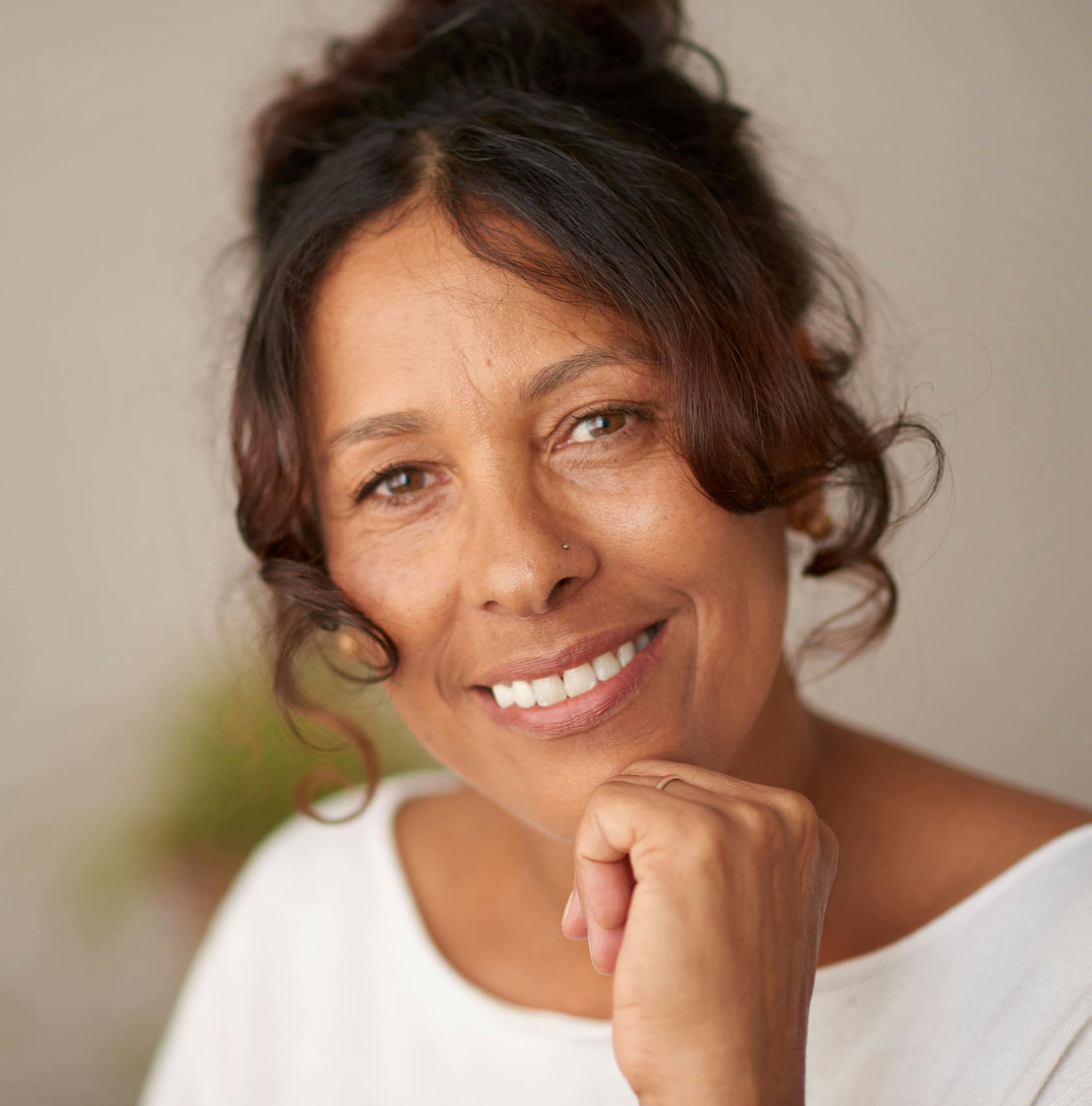woman smiling with her hand on her chin with her hair tied up
