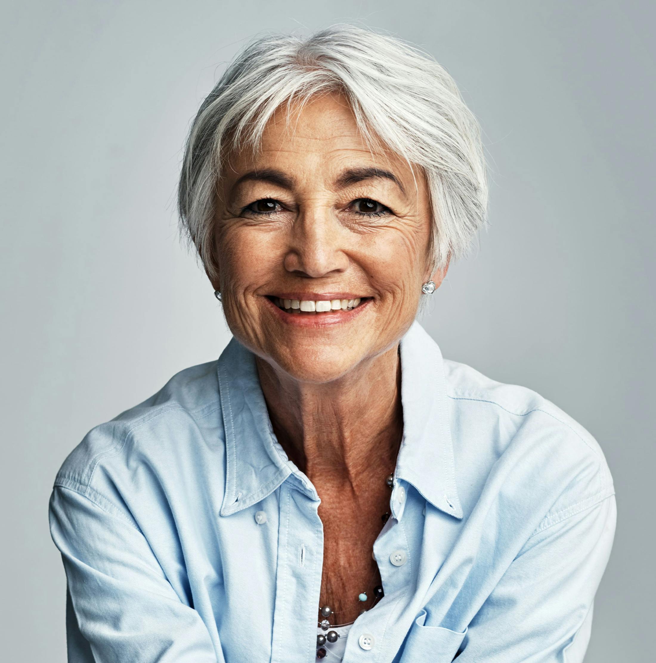 older woman with short, white hair smiling forward