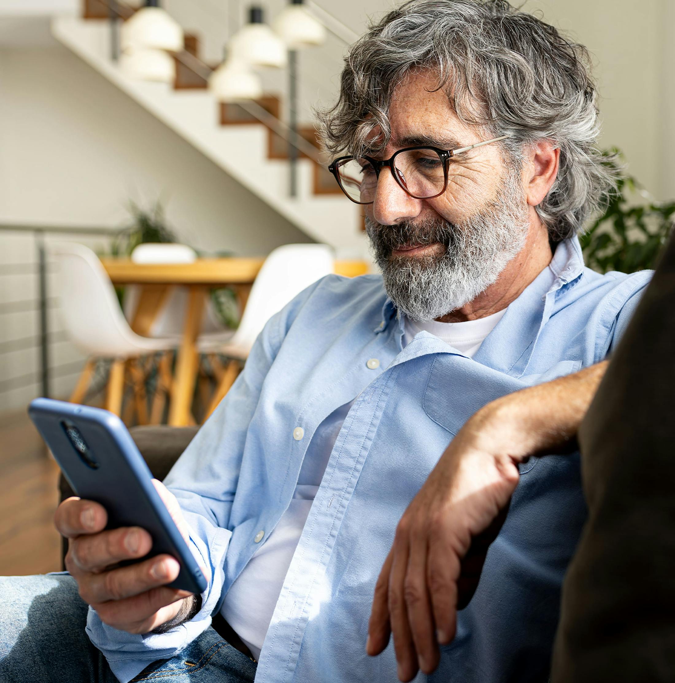 older man on his phone while sitting on the couch