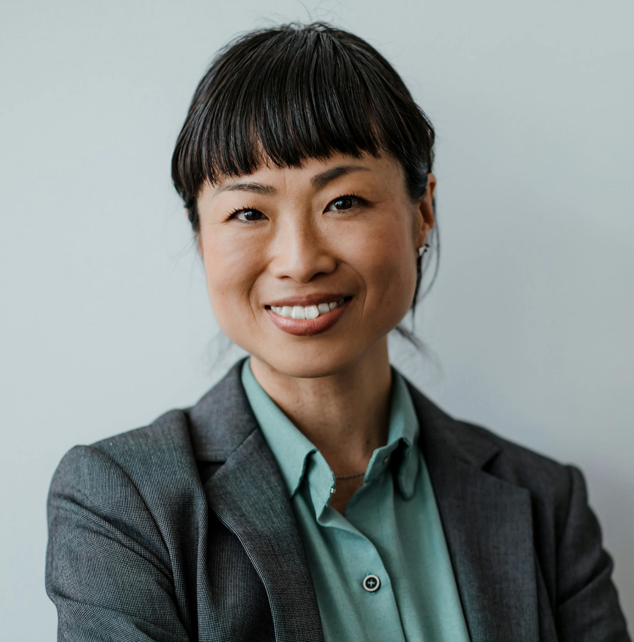 woman with bangs smiling while wearing suit jacket