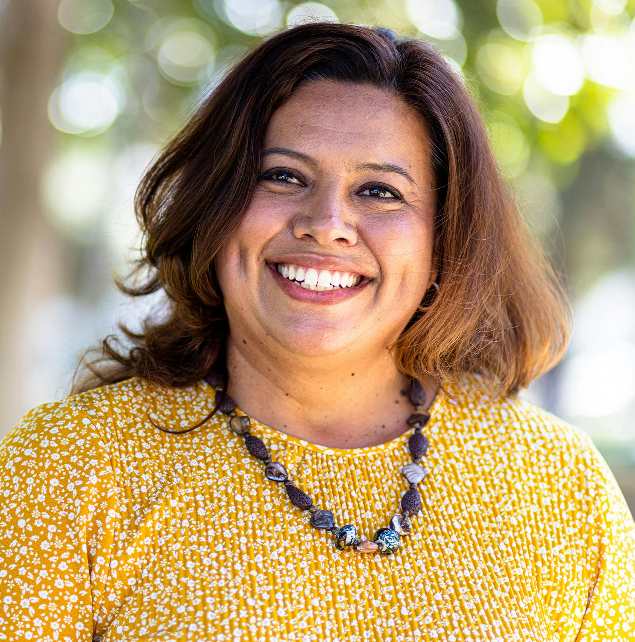woman smiling in yellow shirt outside