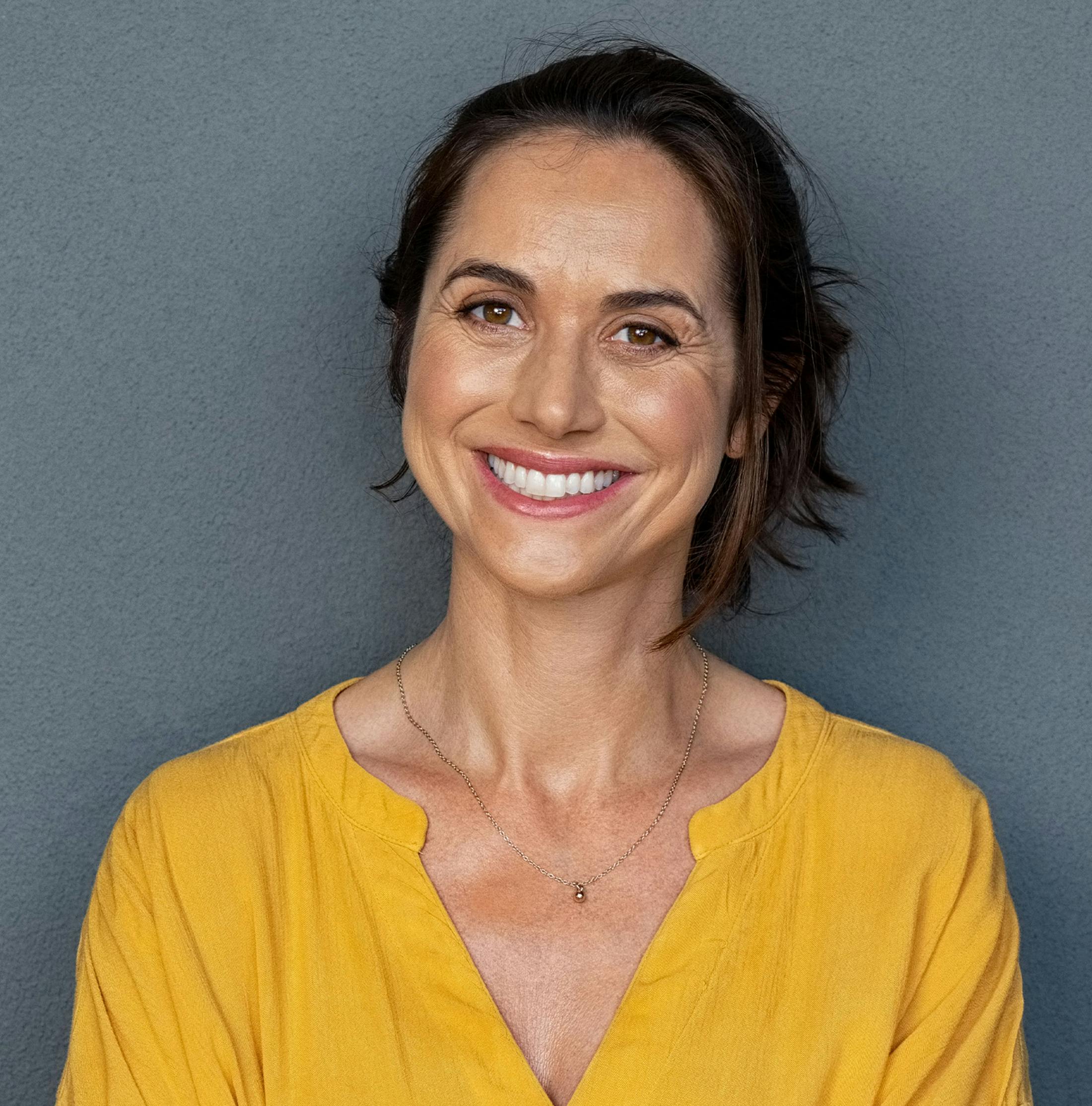woman in bright yellow shirt smiling forward