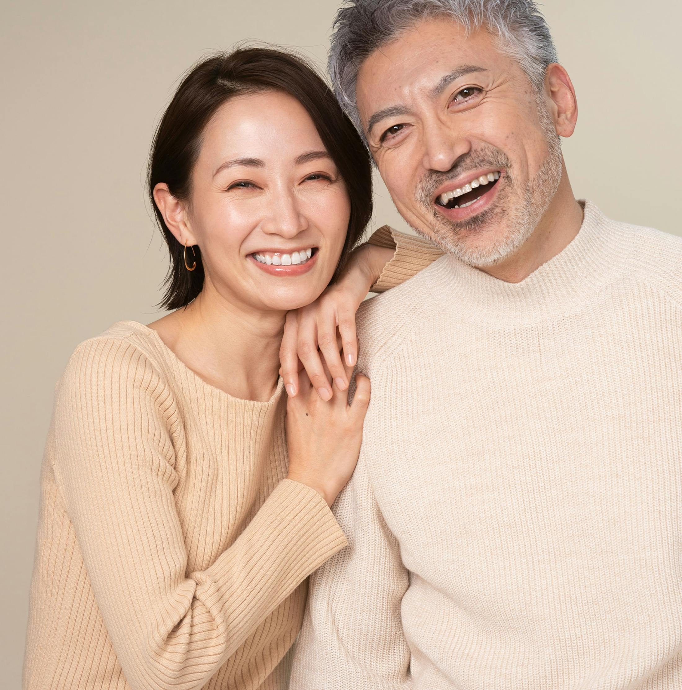 asian couple smiling together with woman's arm on the man's shoulder