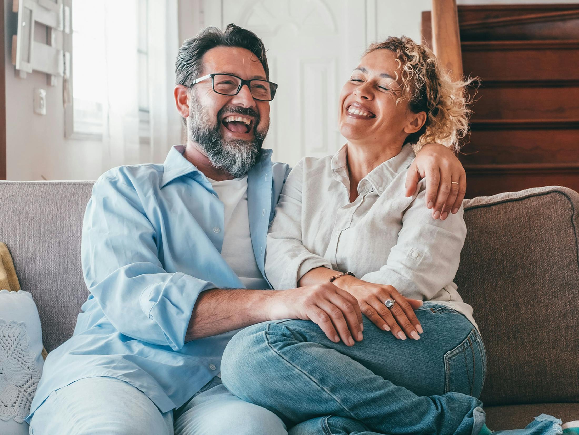 couple sitting on couch together with his hand around her shoulder