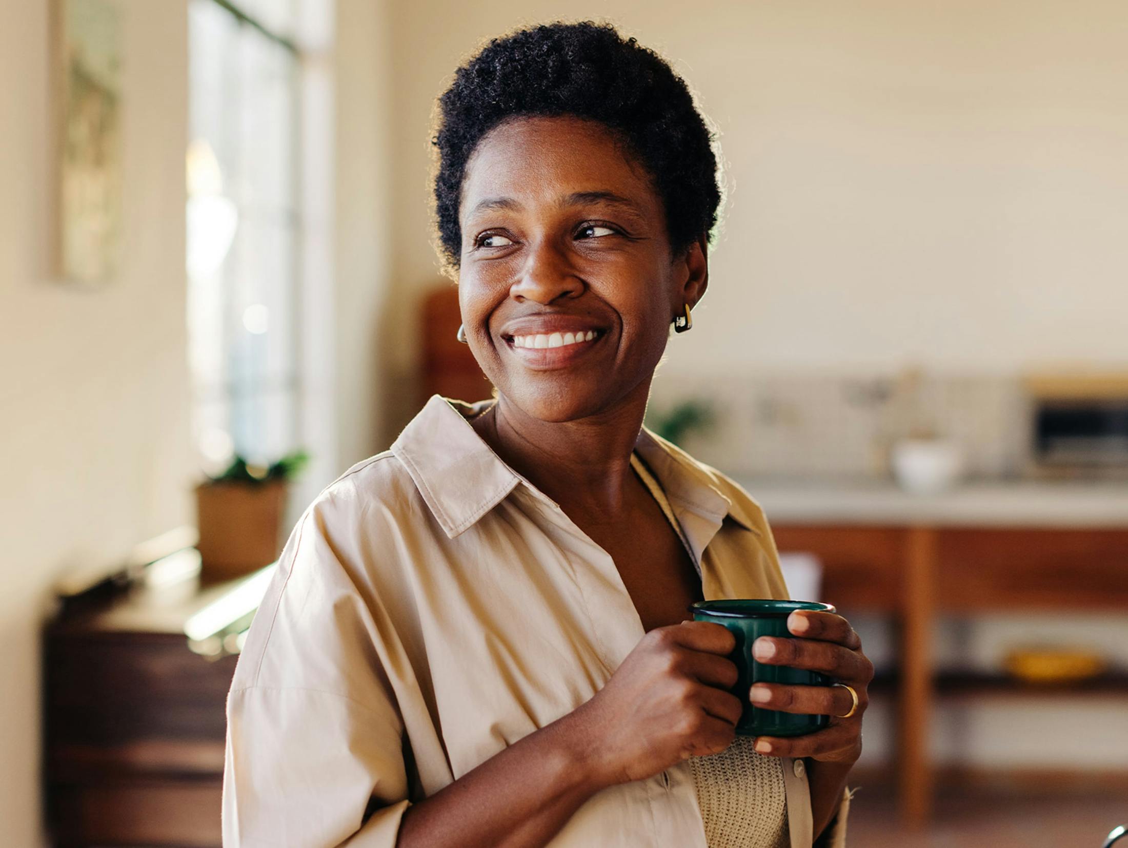 woman holding a green mug while smiling