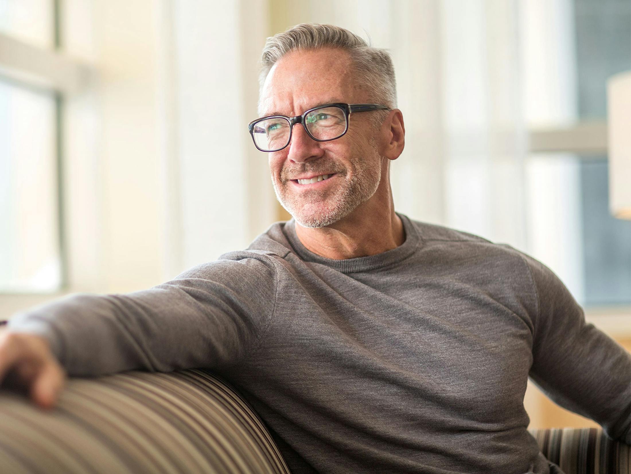 man sitting on couch looking behind him through the window