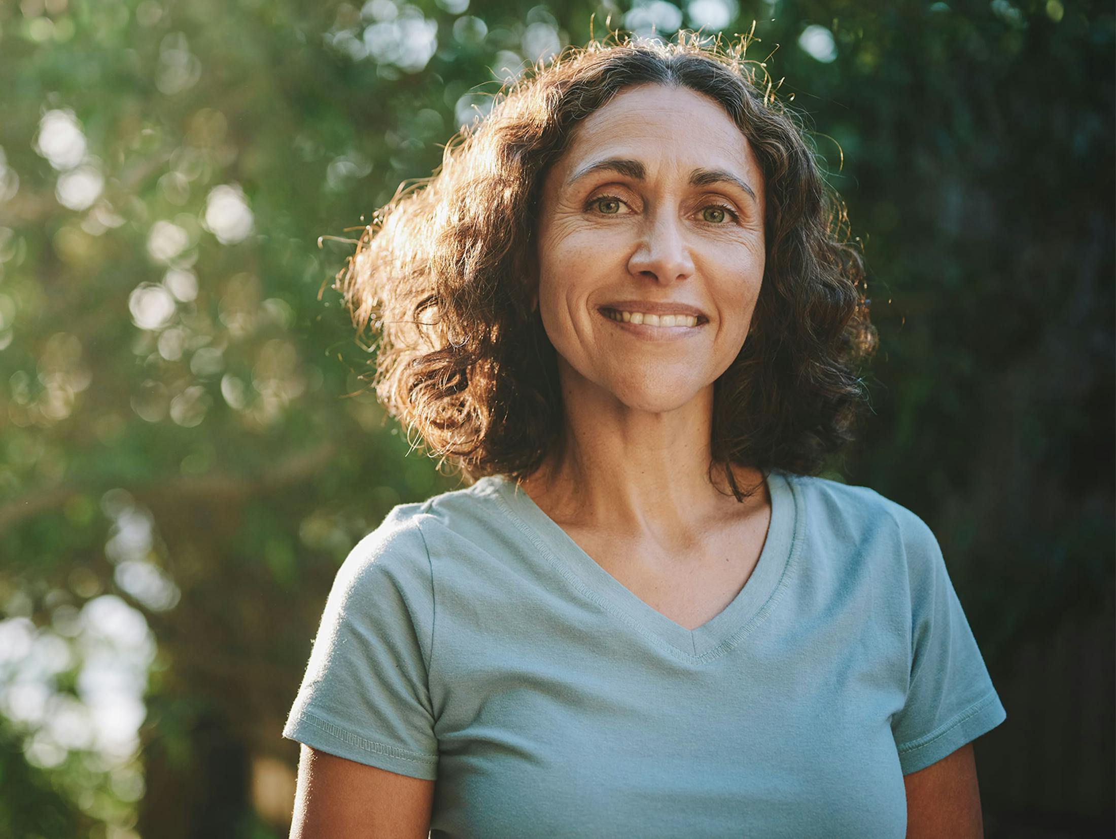 woman outside smiling with short curly hair