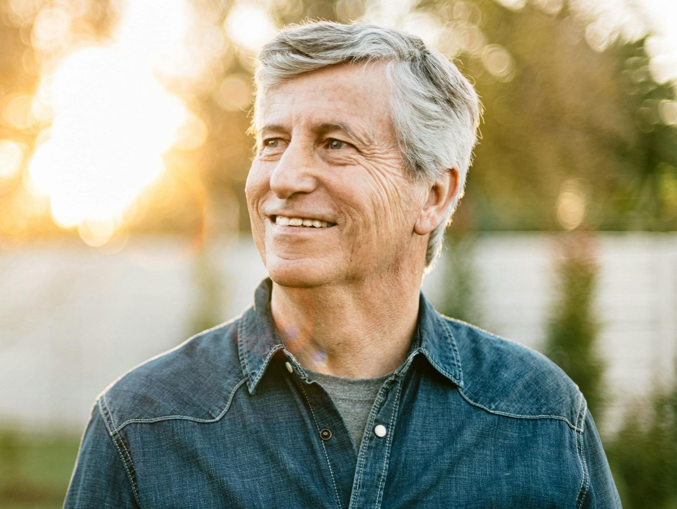 man smiling outside with jean jacket on