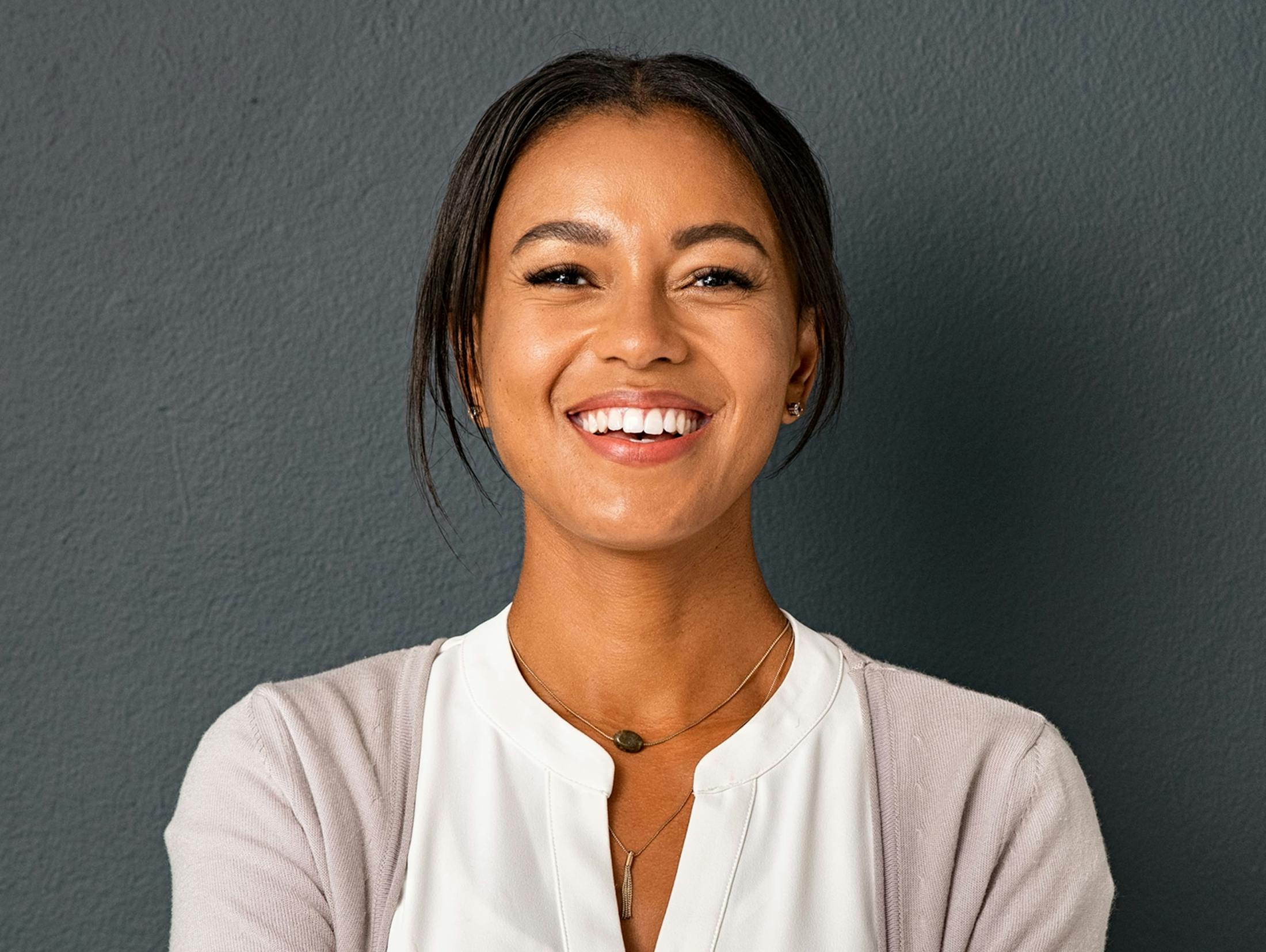 woman smiling while standing in front of dark grey wall