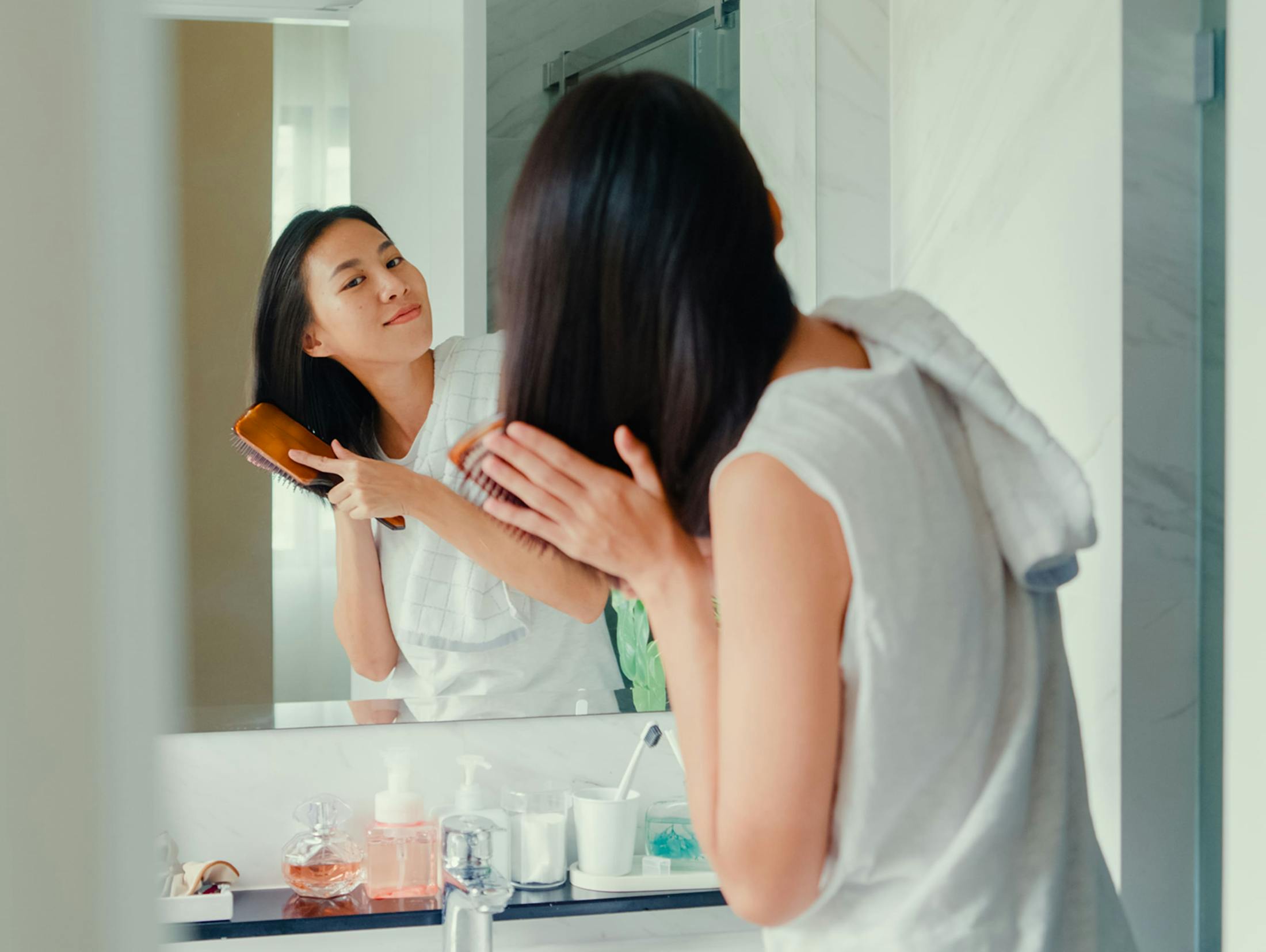 woman brushing her hair in the mirror