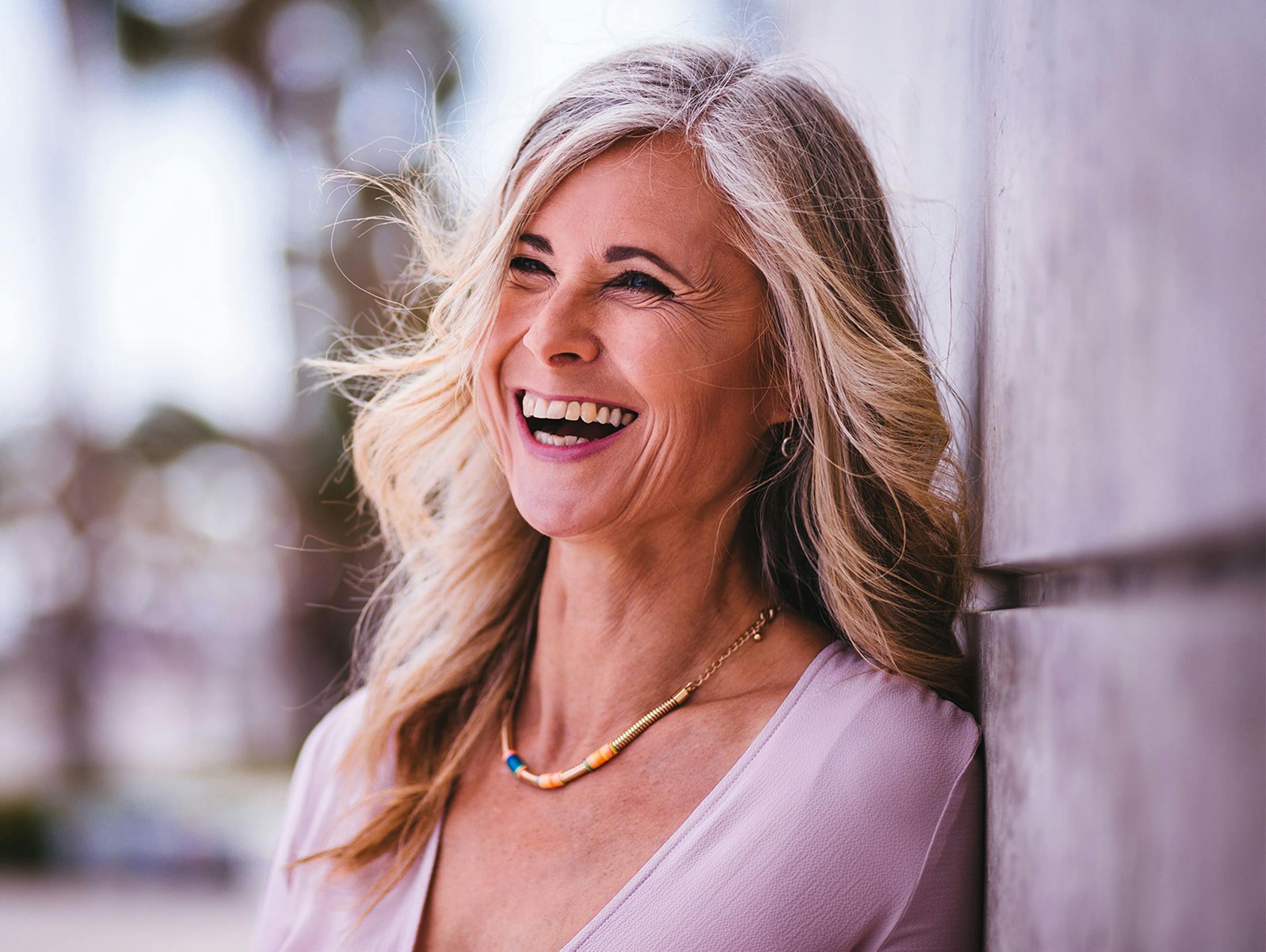 woman with blonde hair leaning against wall