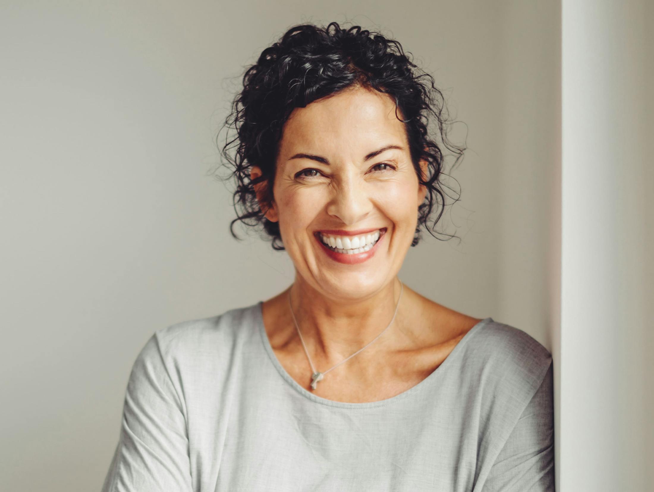 woman smiling and leaning against wall
