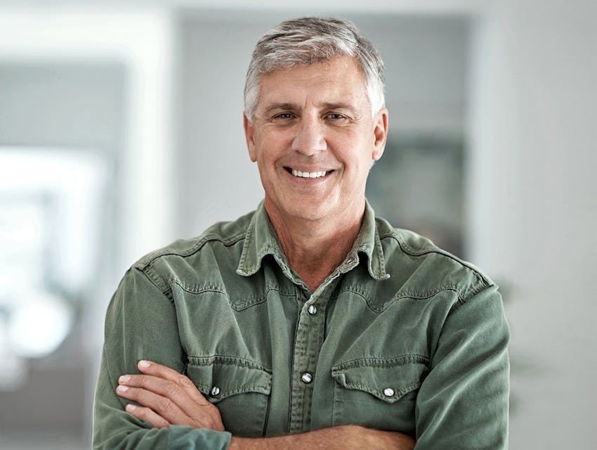 man smiling in green button-up crossing his arms