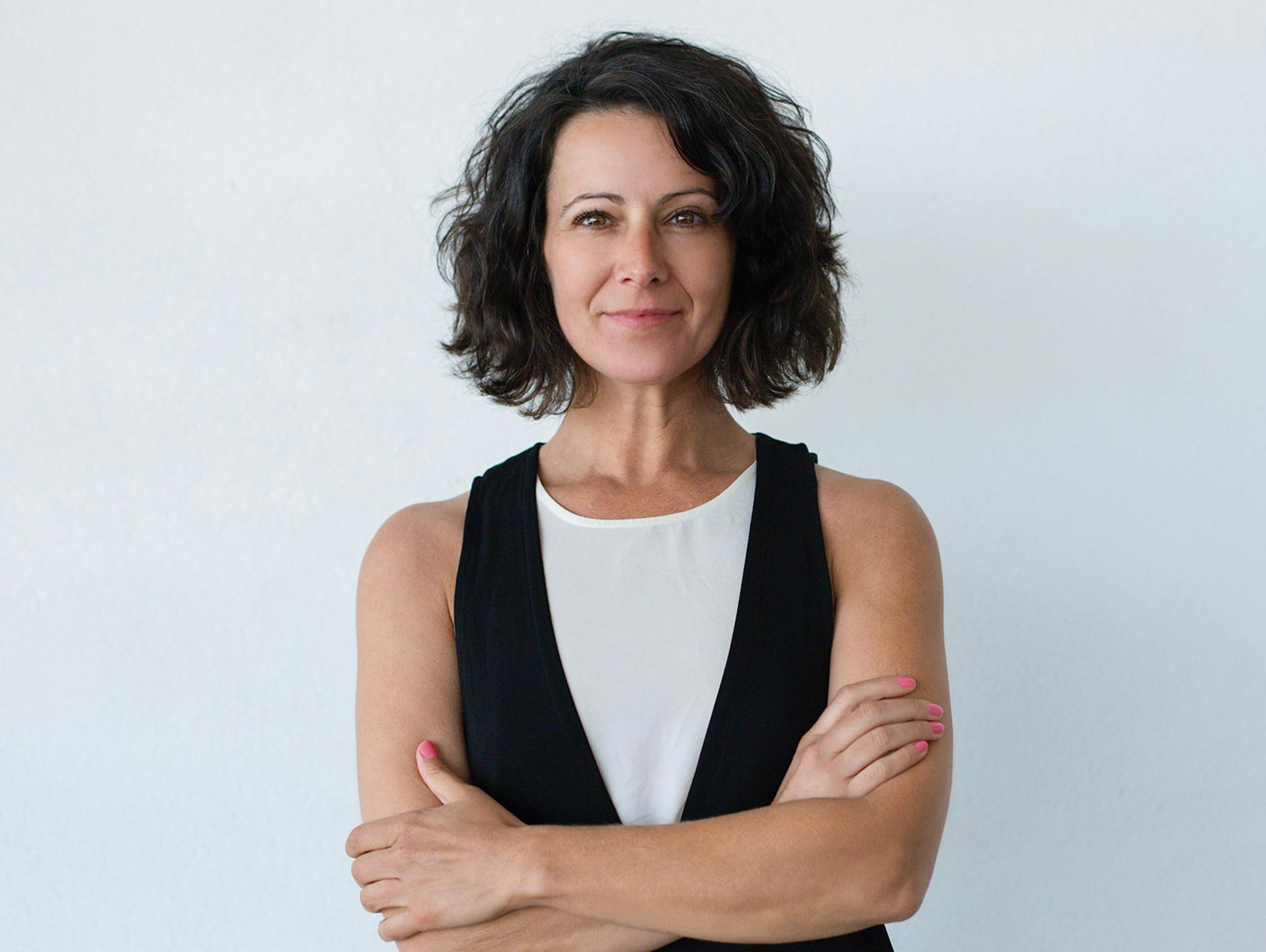 woman standing against white wall with her arms crossed