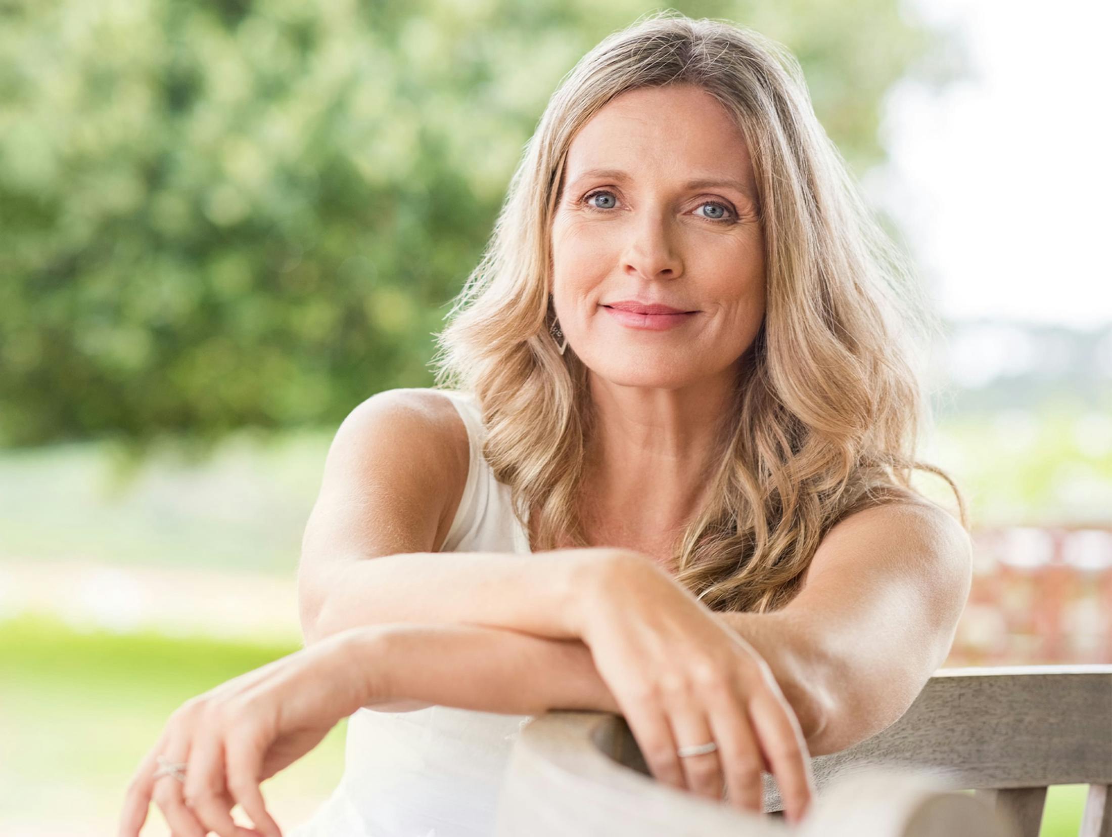 woman sitting on bench with her arms on the railing