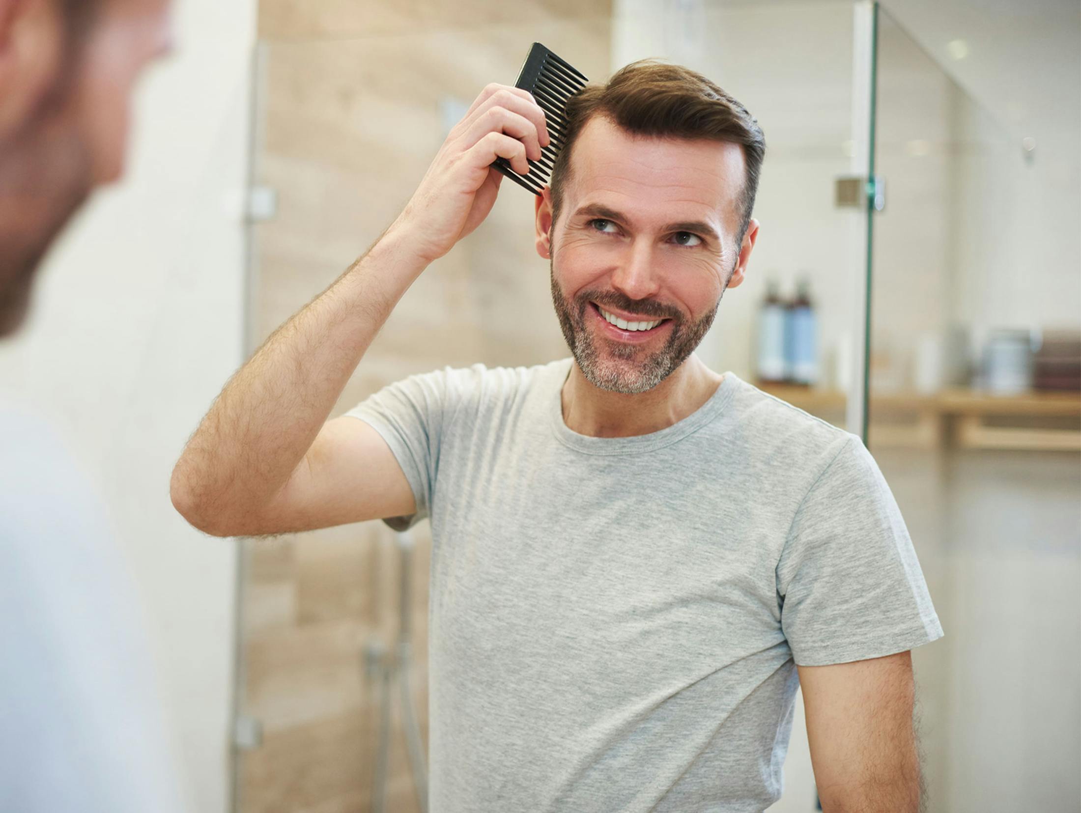 man combing his hair while looking into mirror