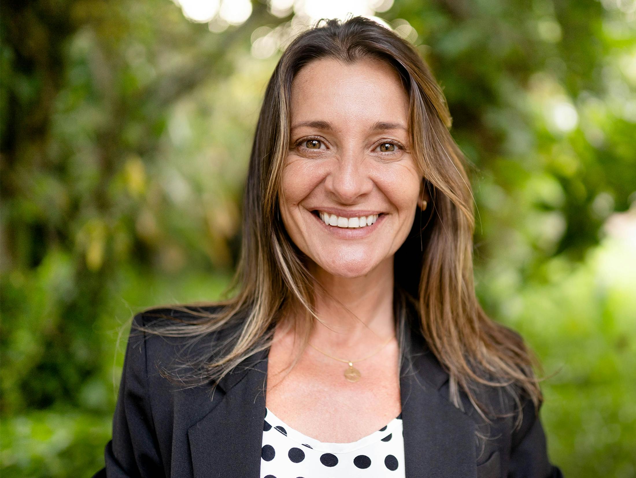 woman outside near trees smiling