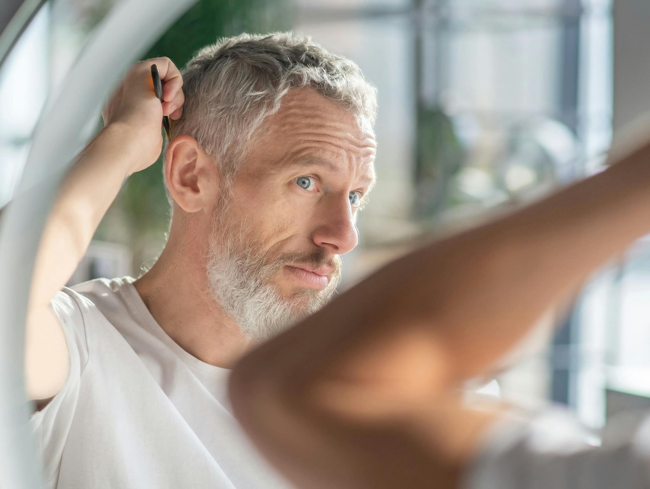 man in mirror combing his hair