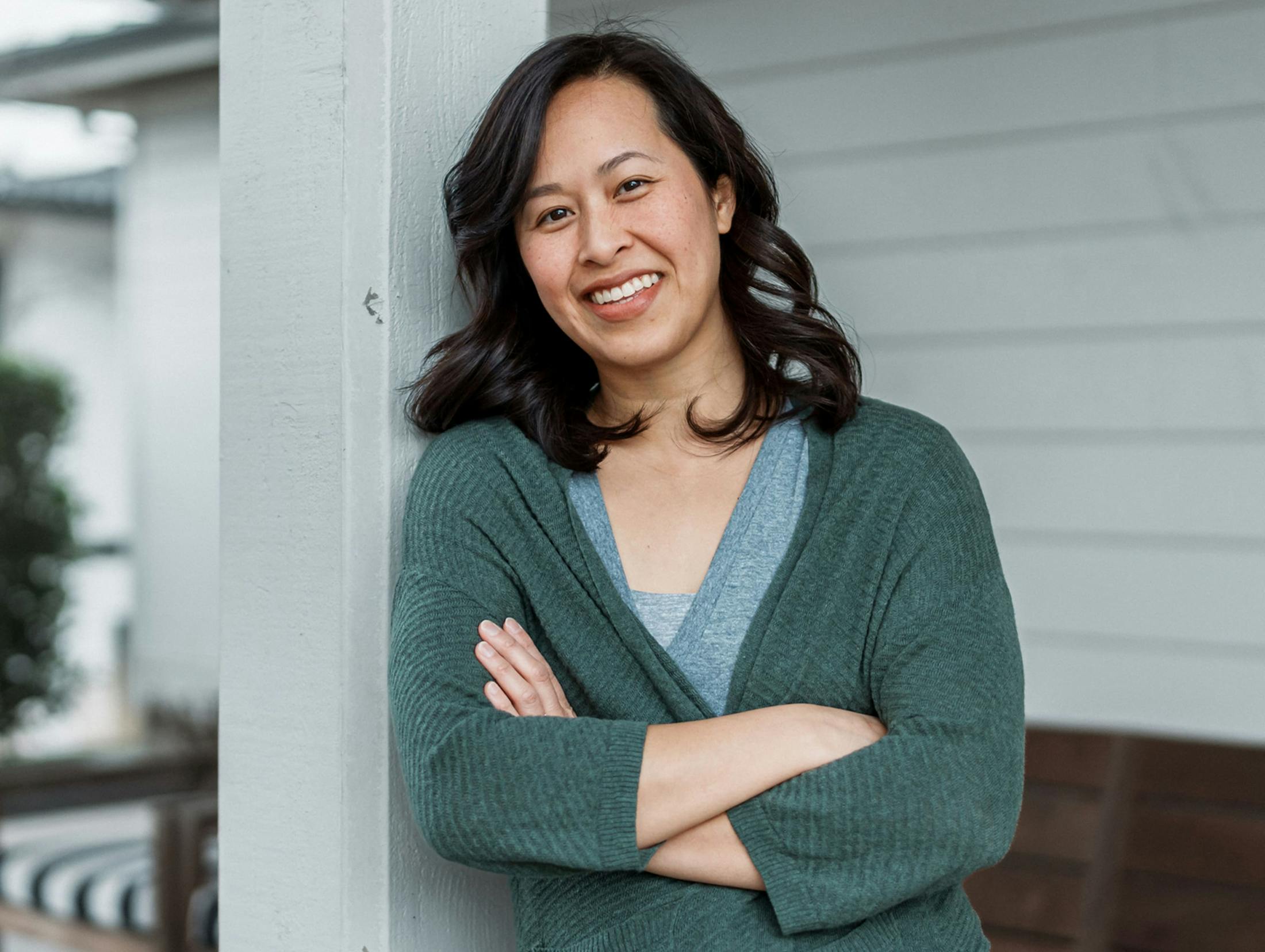 woman leaning on the column of a patio with her arms crossed