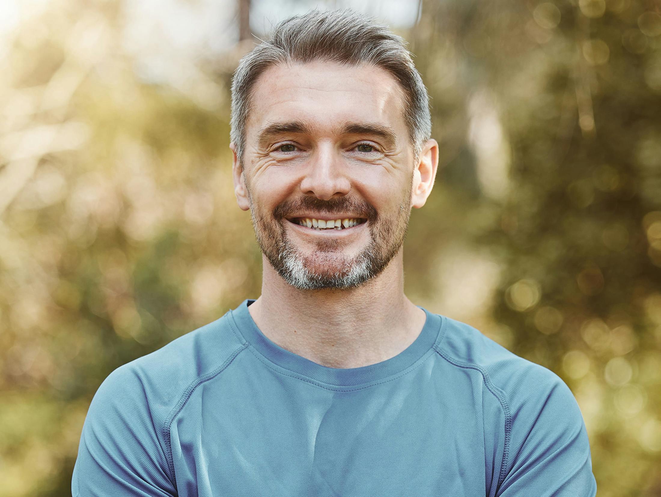man smiling in blue shirt outside