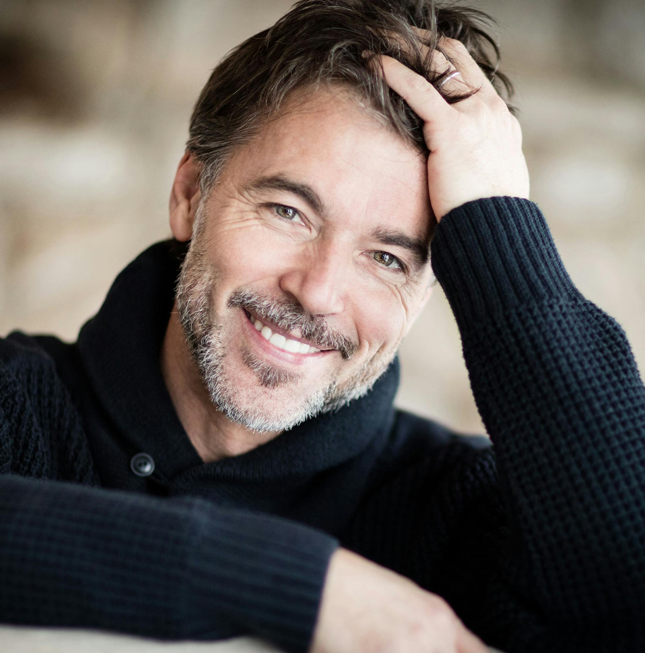 man smiling while combing through his hair
