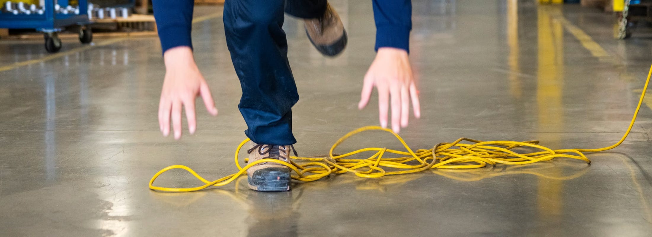 Man tripping on extension cord in warehouse