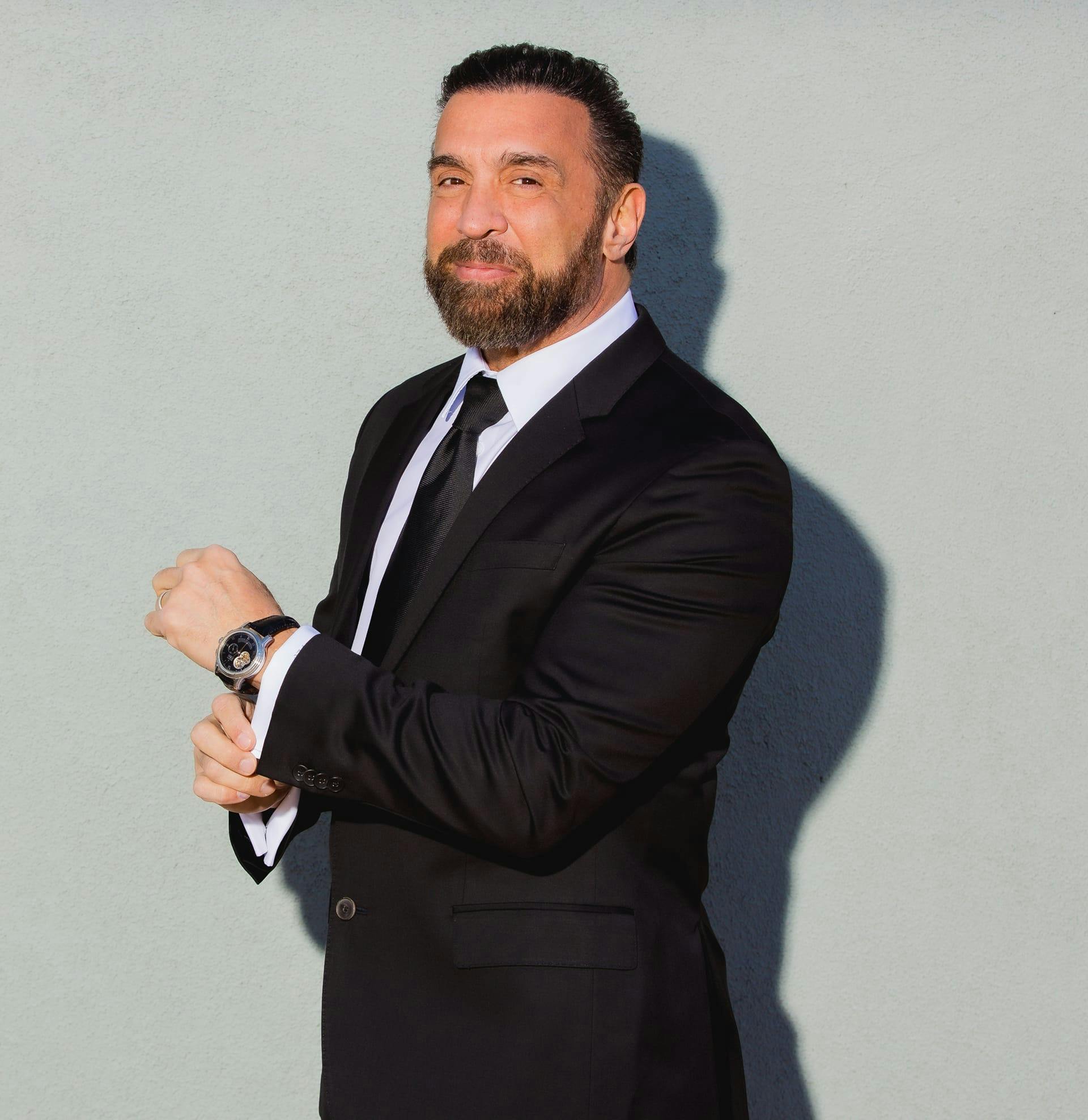 Dr. Frank Stile smiling in a dark suit against a light background