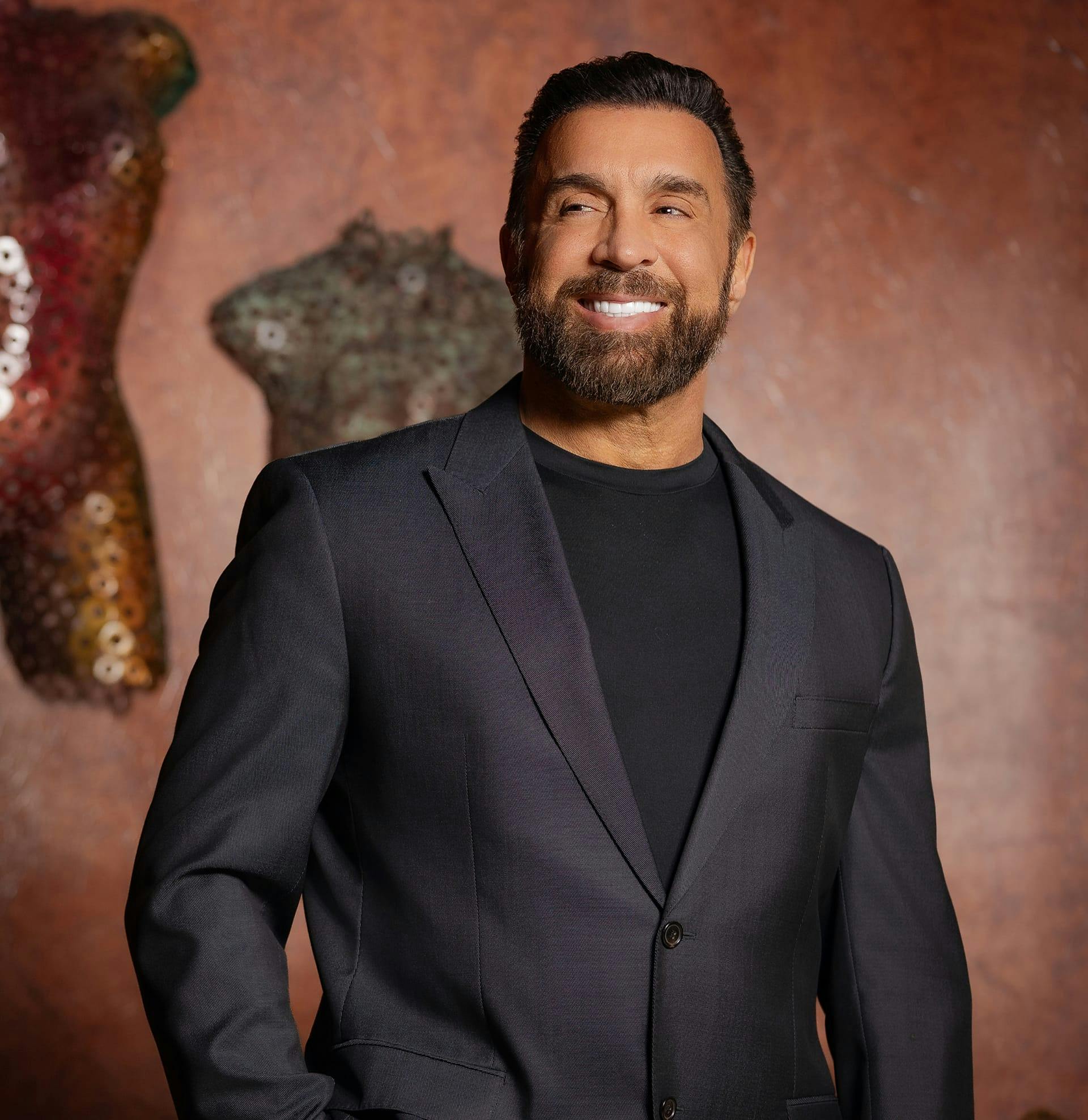 Dr. Frank Stile smiling confidently in dark suit with red backdrop