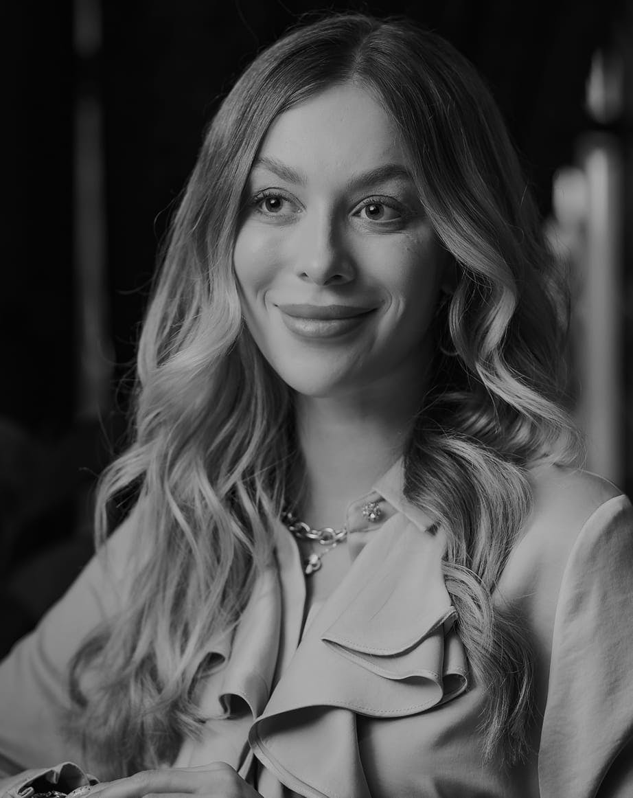 Black and white photo of a smiling woman with loose curls wearing a buttoned shirt