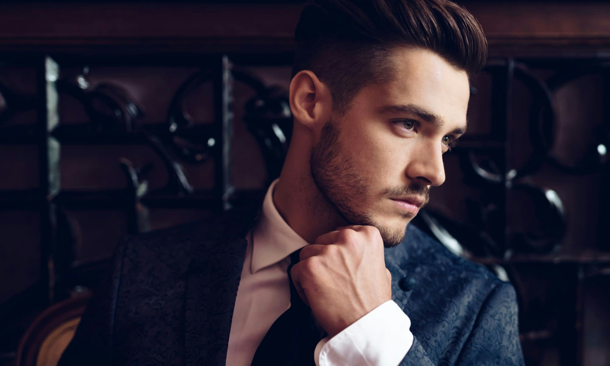 Man with slicked hair touching collar