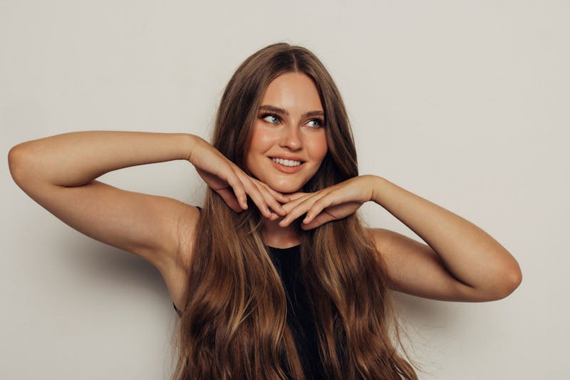 Woman smiling with hands under chin in studio shoot