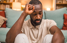 Un hombre está sentado en el suelo de su sala. Está concentrado y con los ojos cerrados.