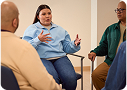 Tres adultos sentados en círculo, conversando. Están en una sesión de terapia de grupo.