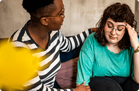 Una mujer conversa afectuosamente con su amiga, una mujer más joven. La abraza.