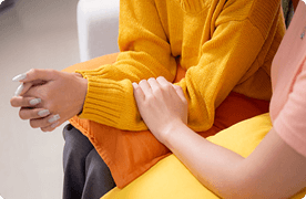 Primer plano de los brazos y las manos de dos personas. Una persona pone una mano sobre el brazo de la otra.