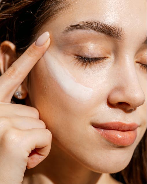 woman putting skincare product on her face