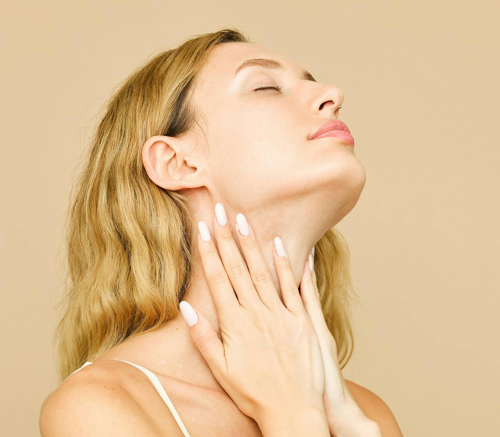 woman lifting her head up and touching her neck