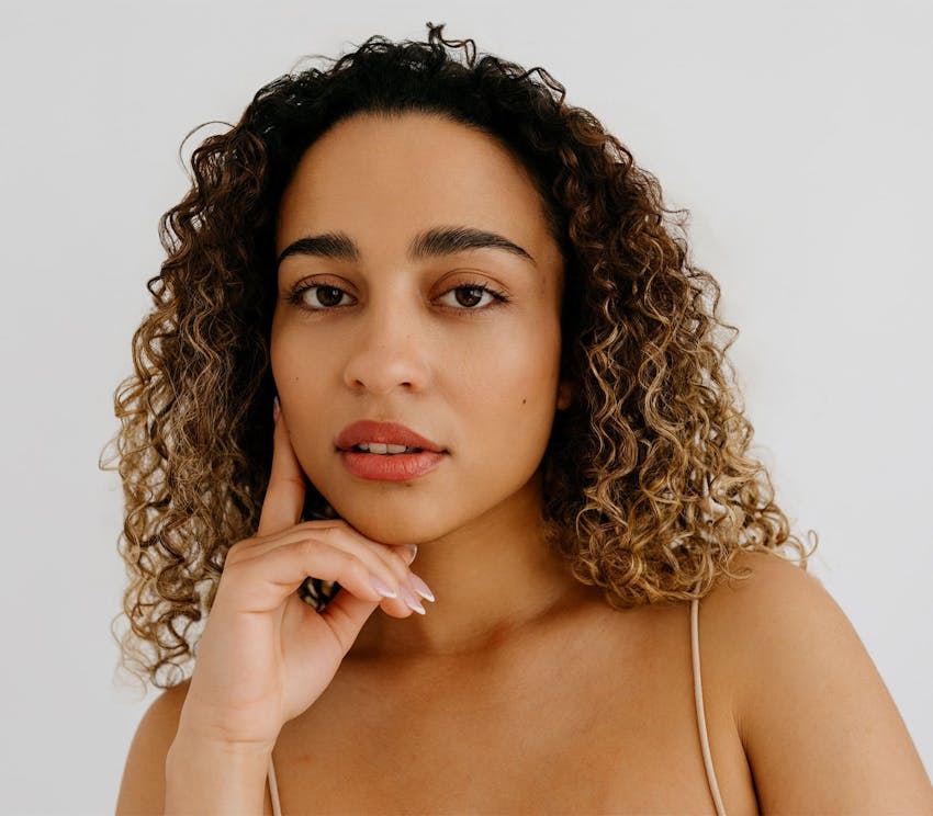 woman with curly hair and hand on her cheek